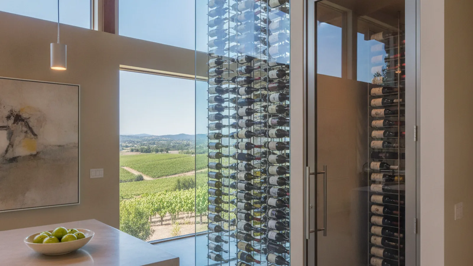 A glazed wine wall beside a dining room, with an enclosed conditioned wine room door beyond it